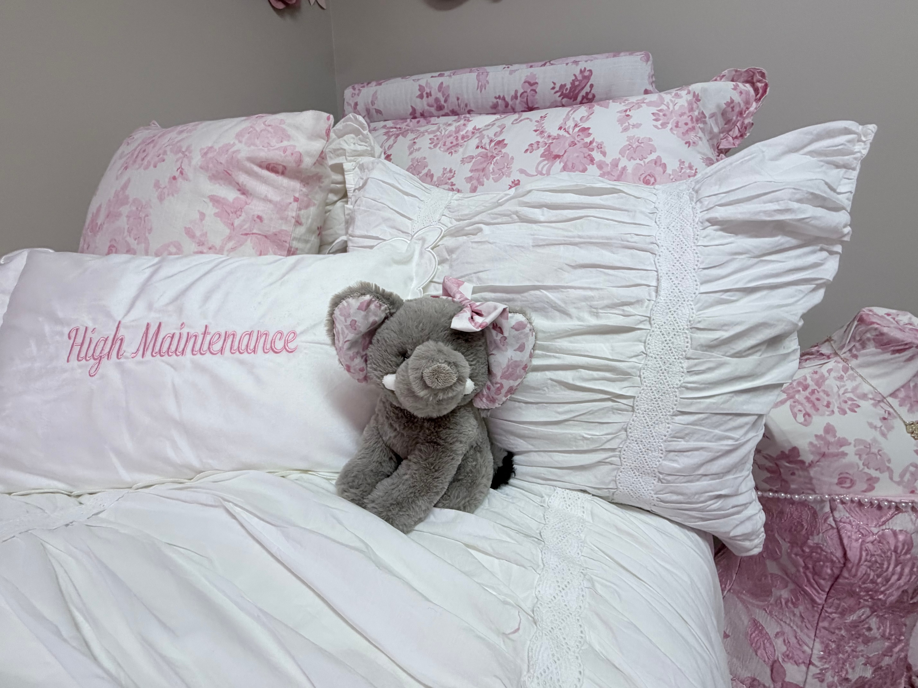 Elephant stuffed animal on pink floral bedding with High Maintenance pillow