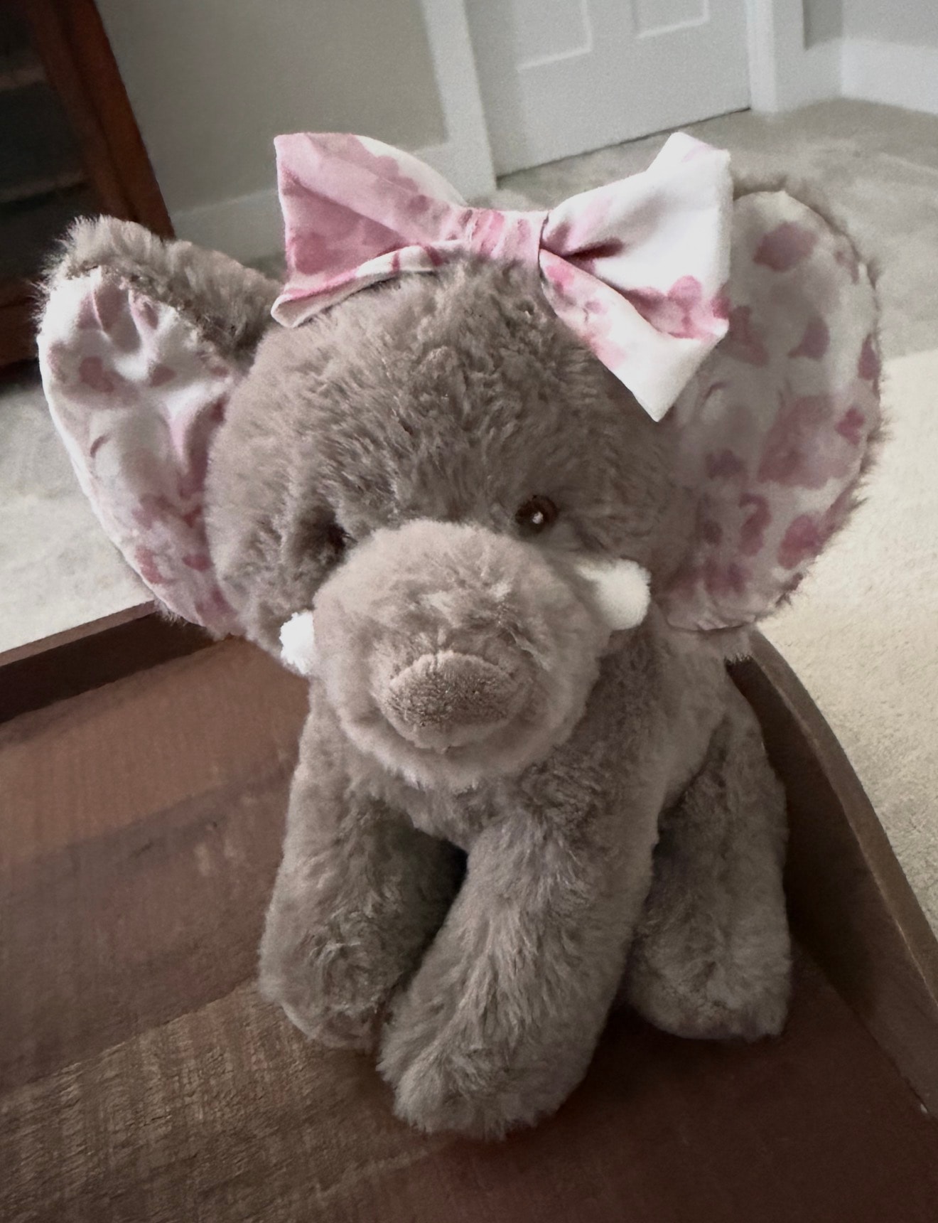 Stuffed elephant with pink floral bow matching room decor