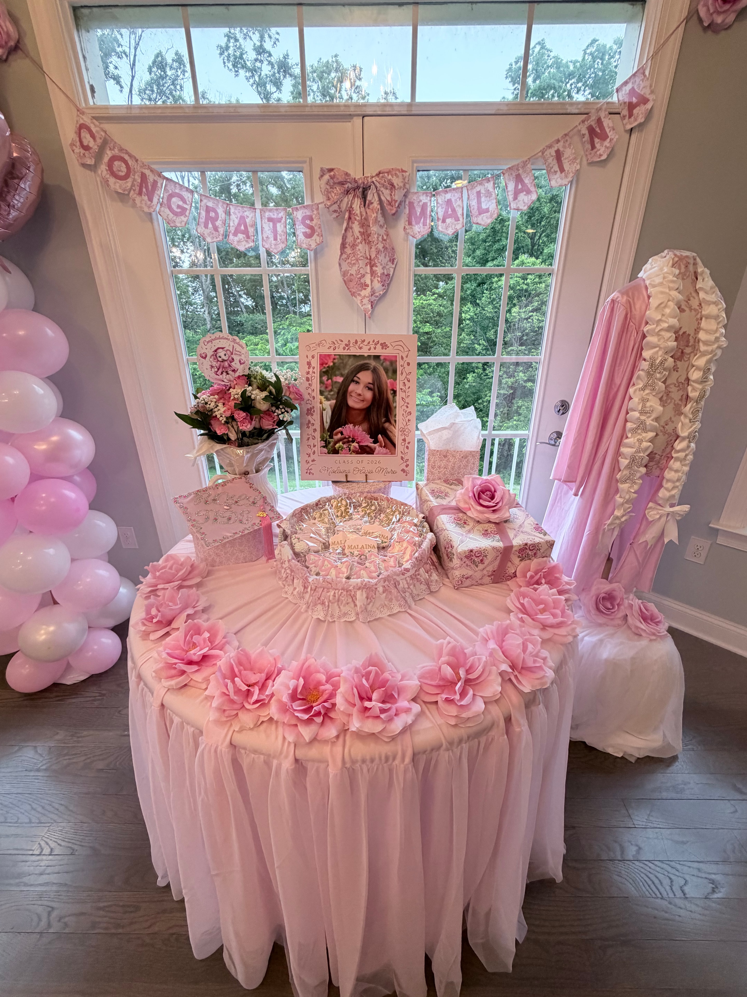 Full graduation display with dress form, pink flowers and Congrats Malaina banner
